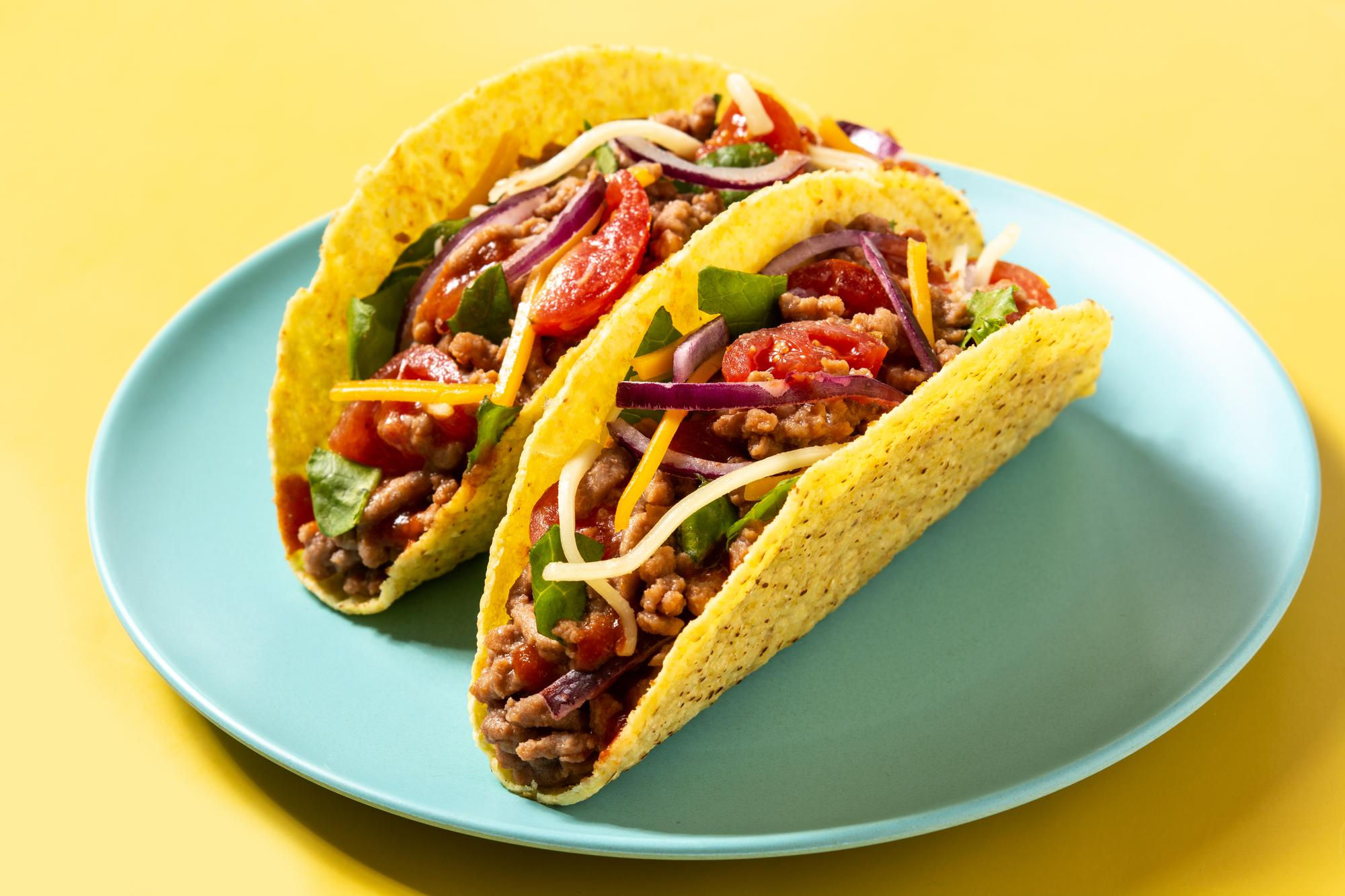 A plate of hard-shell tacos with ground beef and vegetables