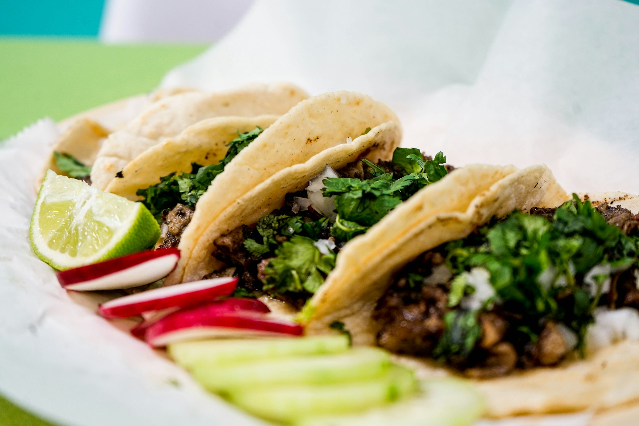 A close-up of several authentic street tacos with cilantro and onion.
